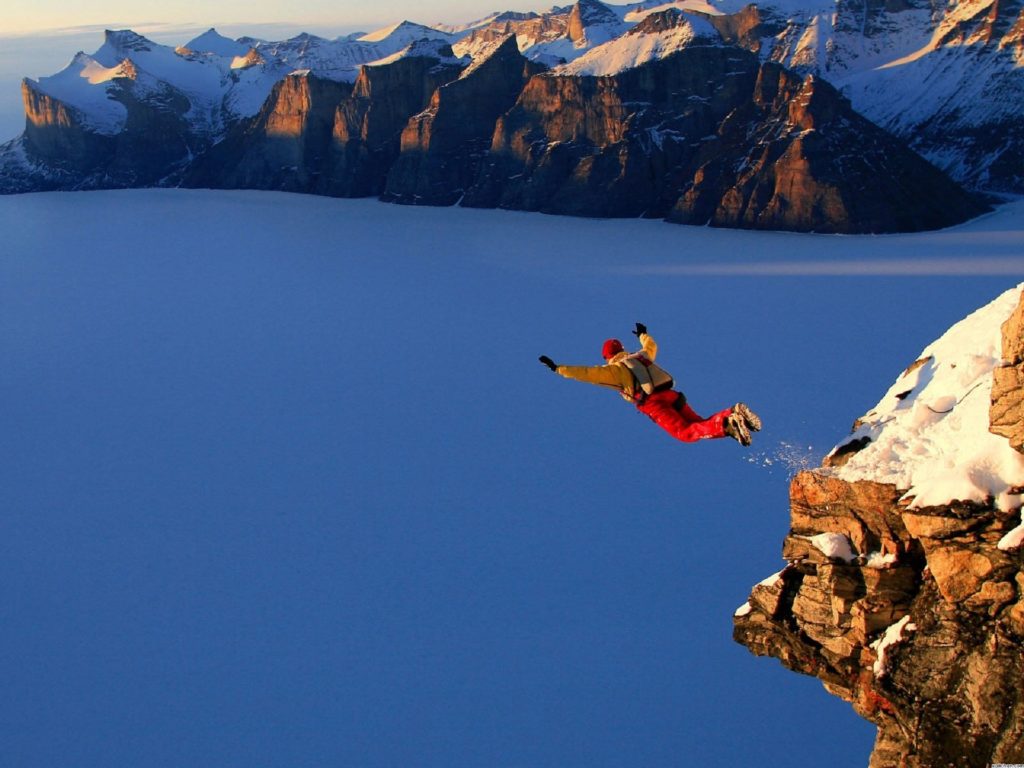 A man base jumping from a high ledge.