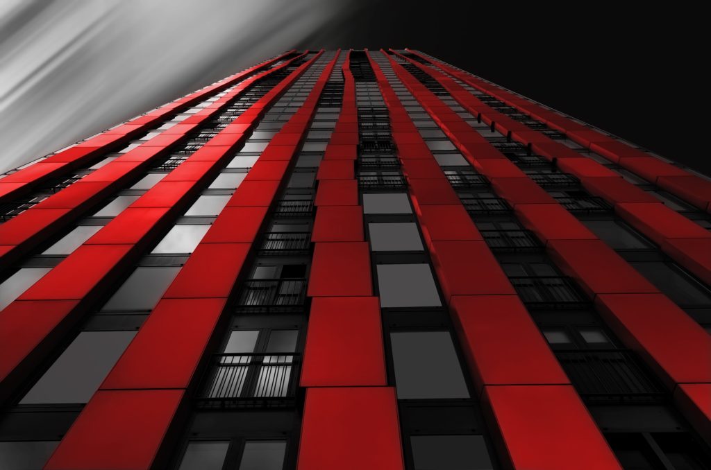 A black skyscraper with red accents extending upwards.