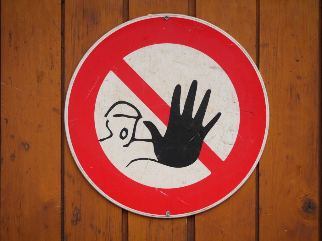 A warning sign depicting a man with his arm stretched out and mouth wide open.