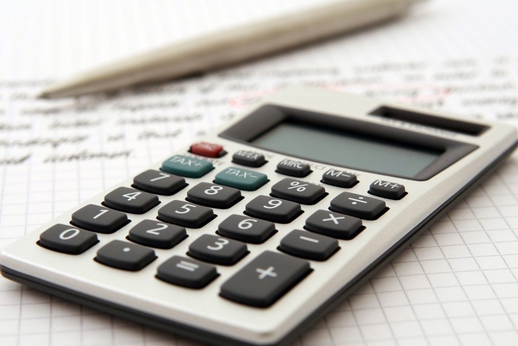 A calculator resting beside a pen.