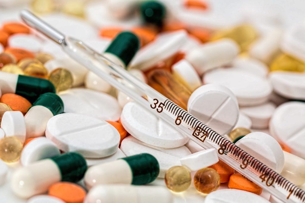 A pile of pills and a medical syringe.