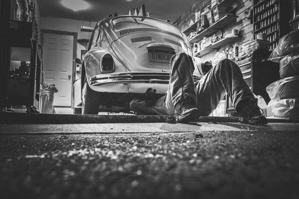 A mechanic underneath a Volkswagen Beetle.