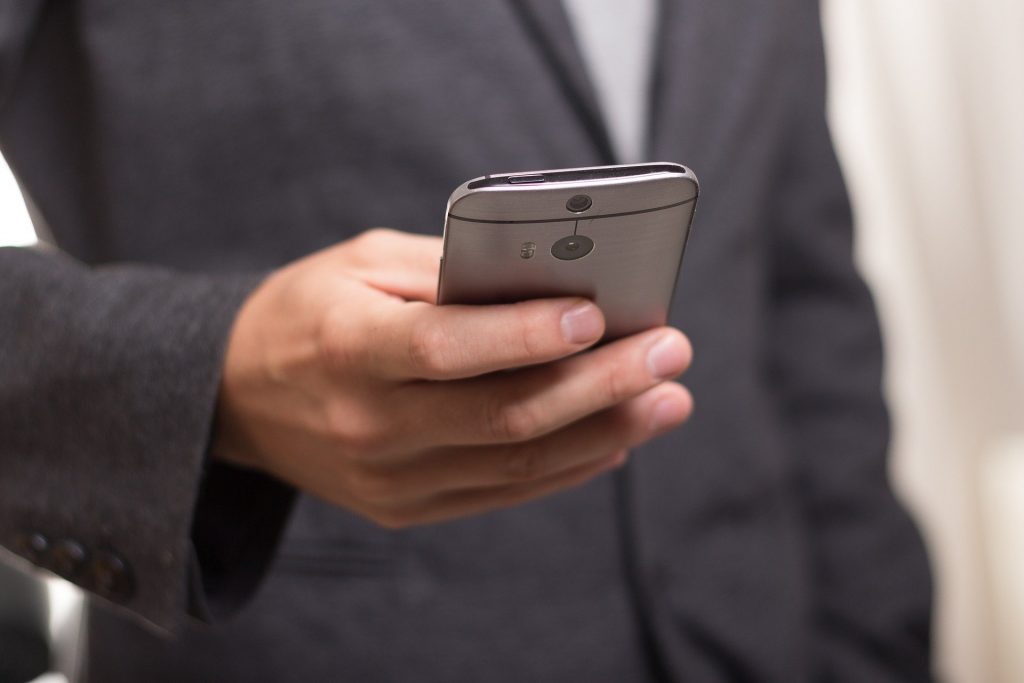 A man in a suit holding and using a smartphone.