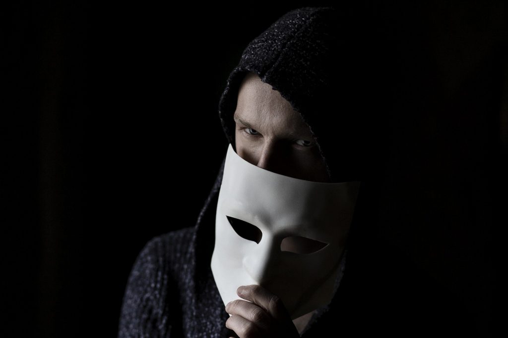 A man holding a mask in front of his face.