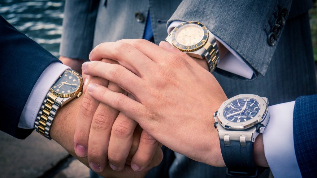 Three hands in a stack with nice watches on their wrists